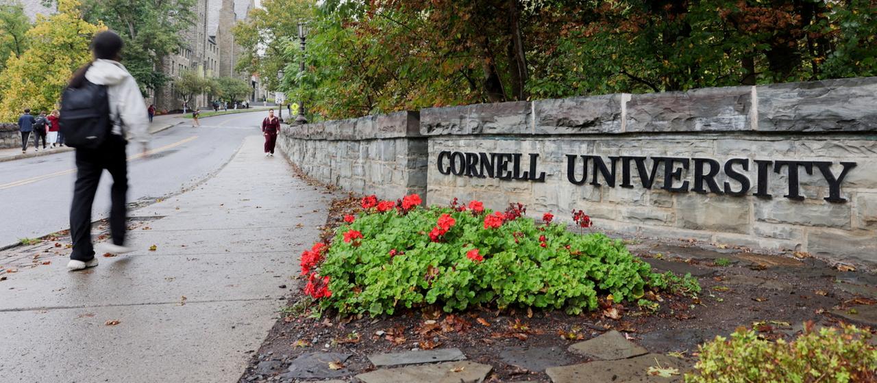 Ein Student geht an einem Schild am Eingang der Cornell University in Ithaca (New York, USA) vorbei.