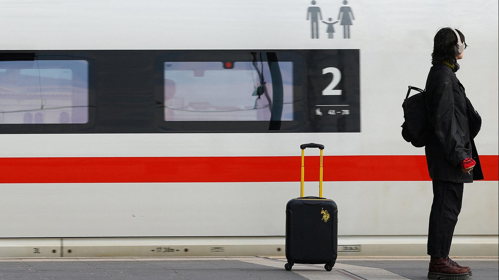 Eine Frau steht mit Gep�ck an einem Bahnhof | REUTERS