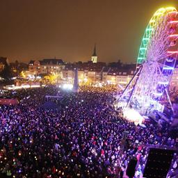 Ein Riesenrad auf dem Erfurter Domplatz. Daneben viele Menschen mit Laternen