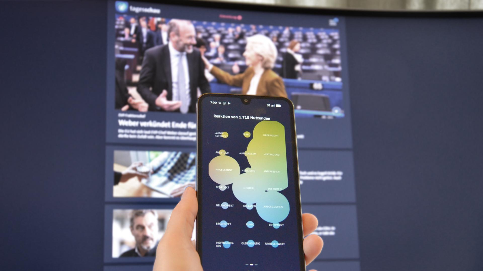 Eine Hand hÃ¤lt ein Smartphone mit der Funktion Emotionale Reaction der tagesschau-App. | ARD-aktuell