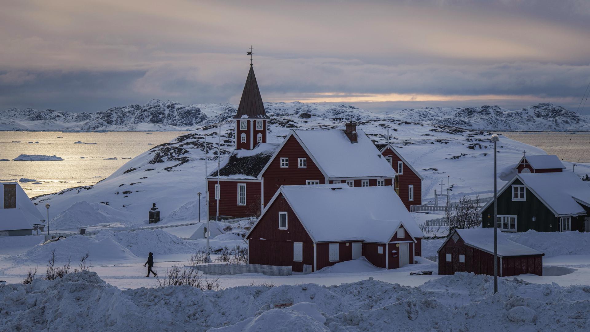 Eine Frau geht in der Nähe einer Kirche in Grönland.  | dpa
