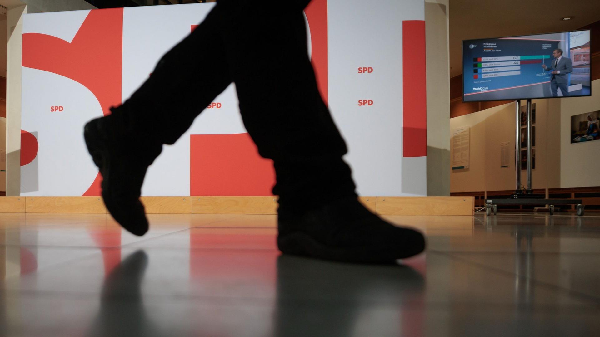 Ein Mann geht im Willy-Brandt-Haus an der großen Wand mit dem SPD-Parteilogo vorbei. | Carsten Koall/dpa