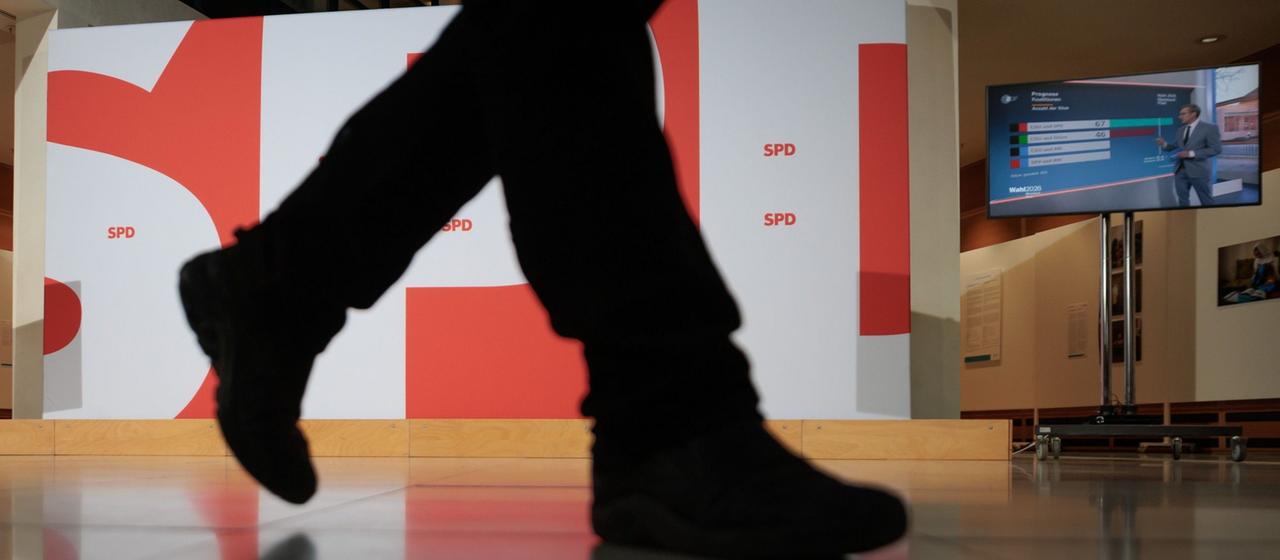 Ein Mann geht im Willy-Brandt-Haus an der großen Wand mit dem SPD-Parteilogo vorbei.