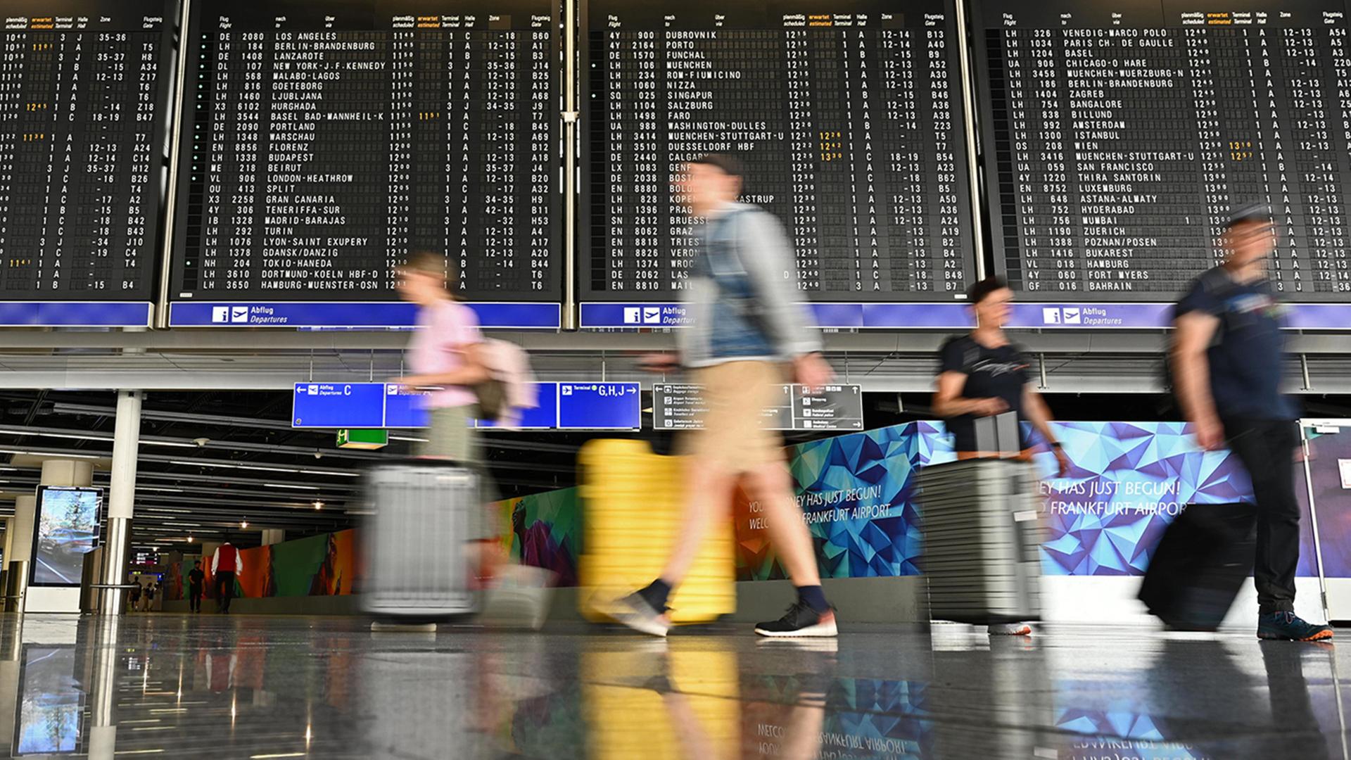 Urlauber laufen im Terminal 1 am Frankfurter Flughafen an einer großen Anzeigetafel vorbei. | Jennifer Brückner/dpa