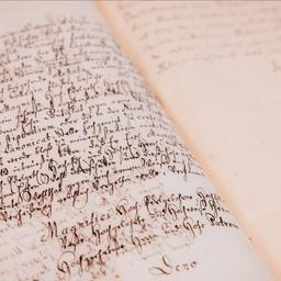 Blick auf historische Papierseiten, in alter Schreibschrift sind geschriebene Zeilen zu erkennen.