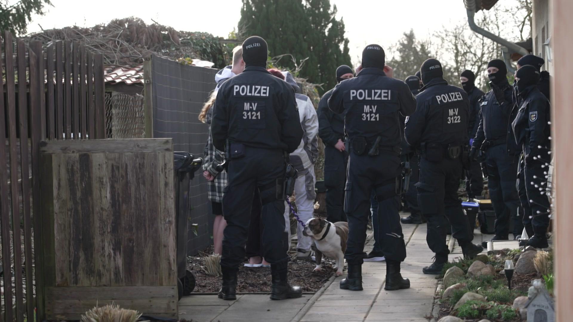 Polizisten stehen bei einer Razzia neben einem Haus. | NDR