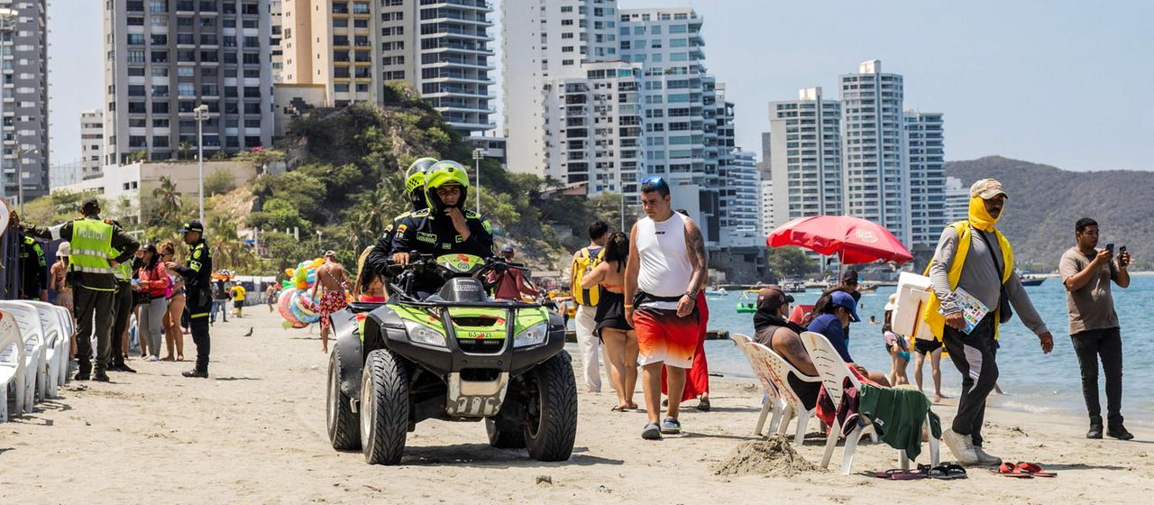 Kolumbianische Polizeibeamte patrouillieren auf einem Quad am Strand in Santa Marta, Kolumbien.