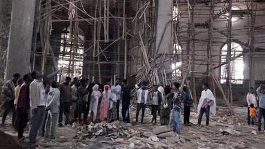 Menschen stehen vor den Trümmern eines hölzernen Baugerüsts in einer äthiopischen Kirche.