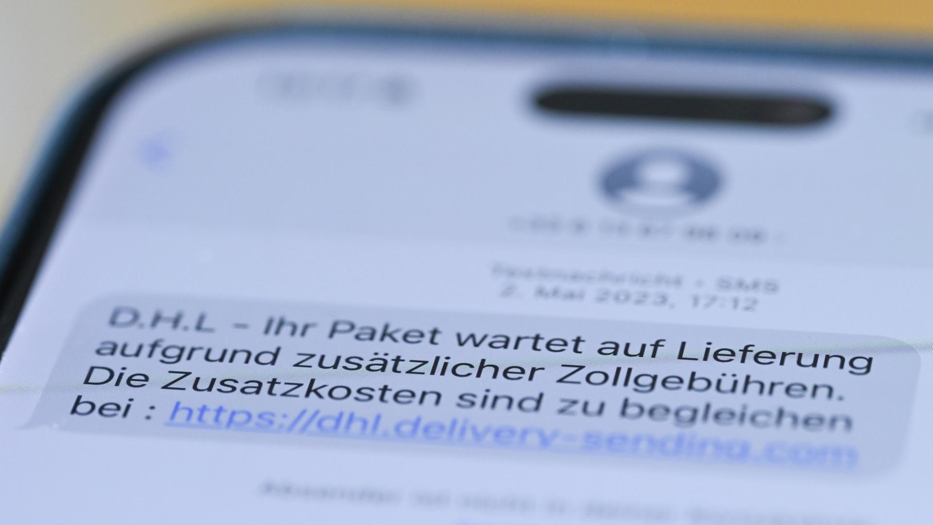 Auf einem Smartphone ist eine Betrugs-SMS zu lesen, in der Kriminelle ein Paket ankündigen und dafür Zollgebühren einfordern. | dpa