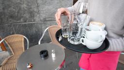 Ein Kellner räumt einen Tisch in einem Restaurant ab.
