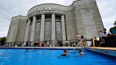 Menschen baden in einem tempor&auml;ren Schwimmbecken vor der Volksb&uuml;hne Berlin.