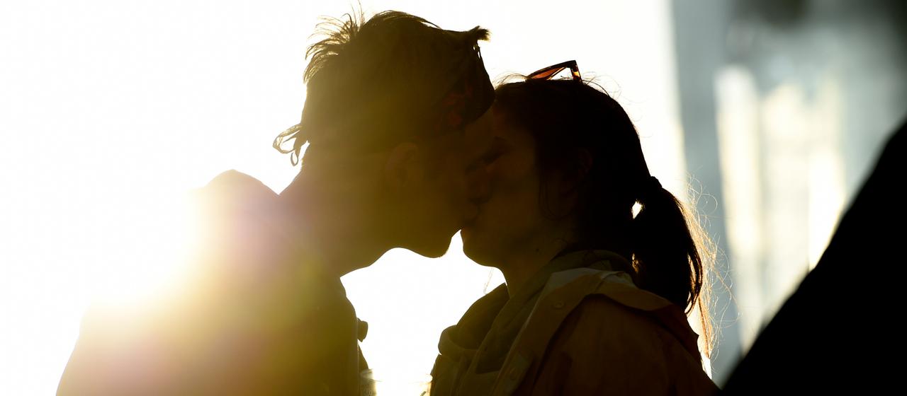 Ein junges Paar küsst sich im Sonnenuntergang.