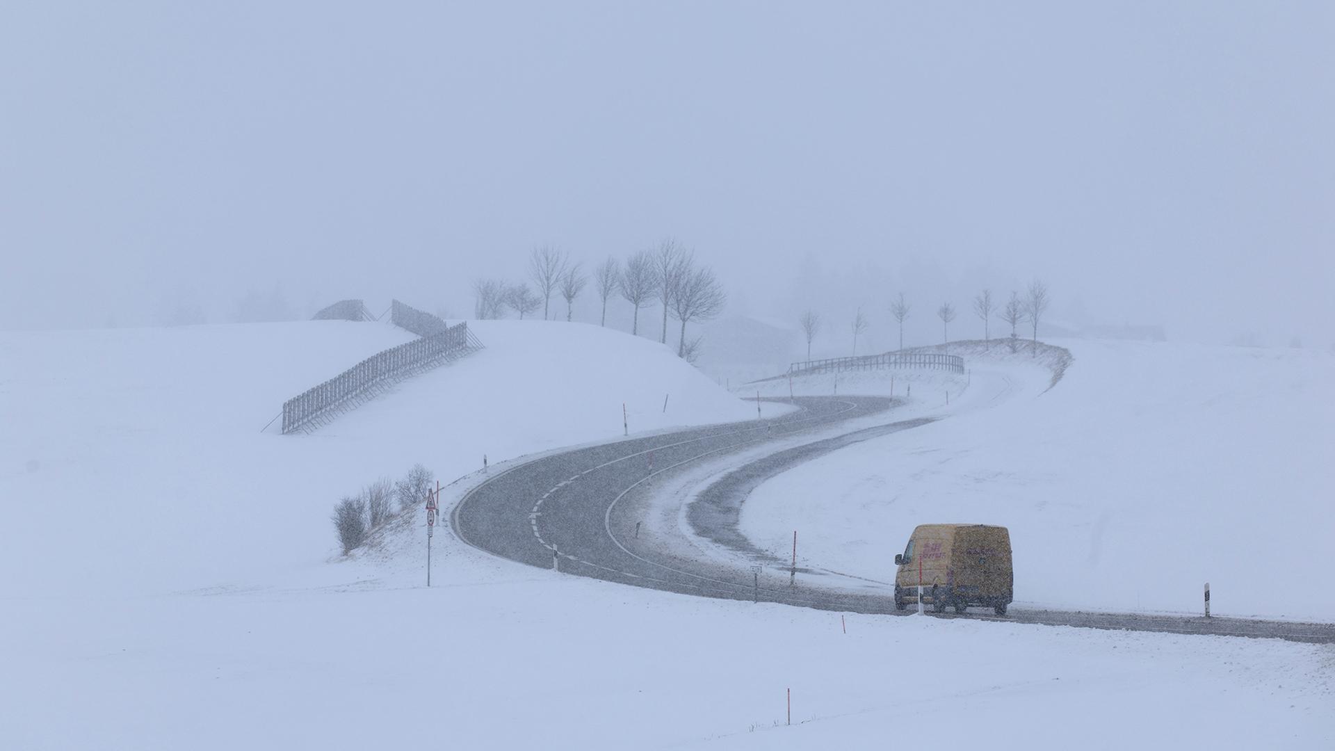 Ein Lieferwagen ist auf einer winterlichen Landstraße unterwegs. | dpa