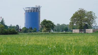 Der Energie- und Zukunftsspeicher der Stadtwerke Heidelberg steht hinter einer mit grünem Gras bewachsenen Wiese.