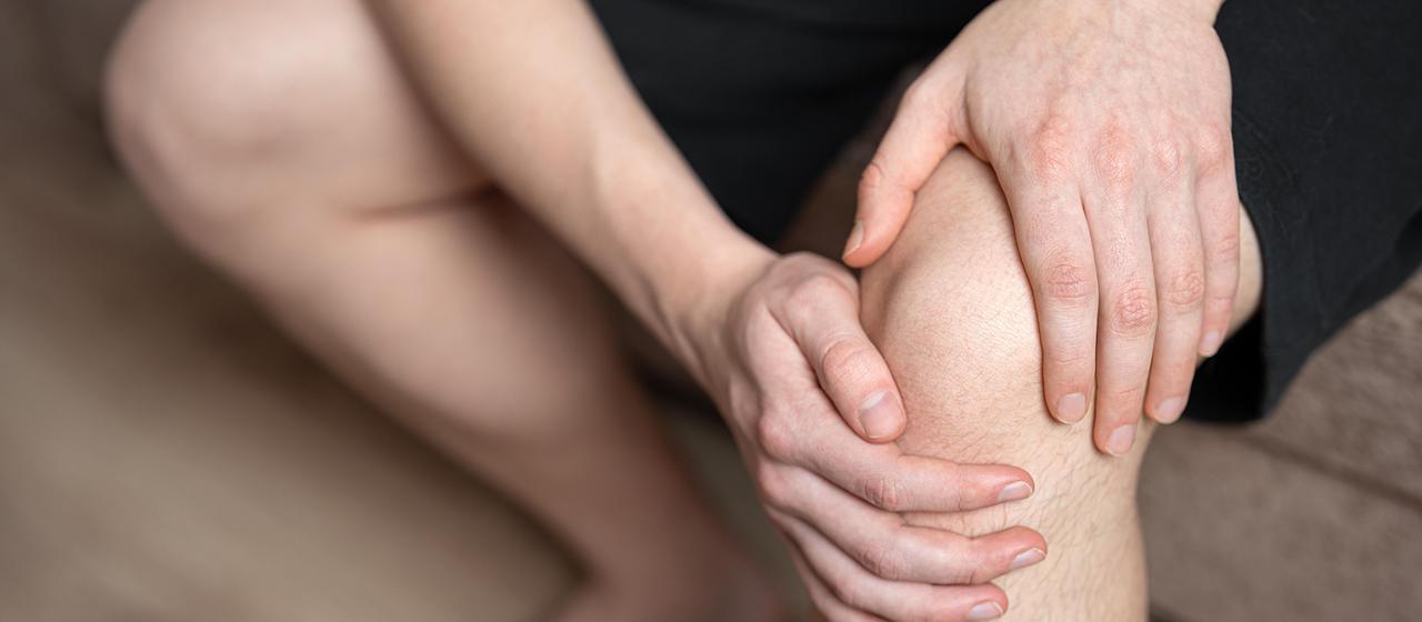 Ein Mann hält sich sein linkes Knie.