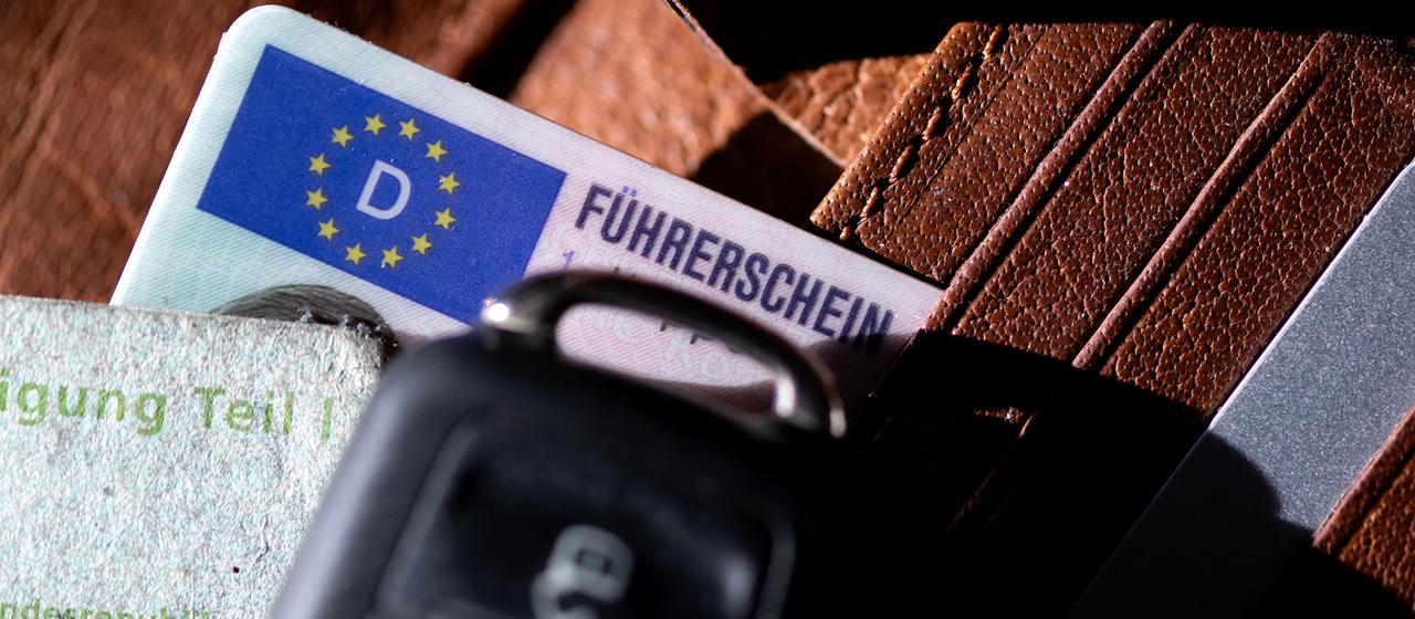 Ein Führerschein, ein Autoschlüssel und eine Zulassungsbescheinigung liegen auf einem Portemonnaie. | dpa Ein Führerschein, ein Autoschlüssel und eine Zulassungsbescheinigung liegen auf einem Portemonnaie.