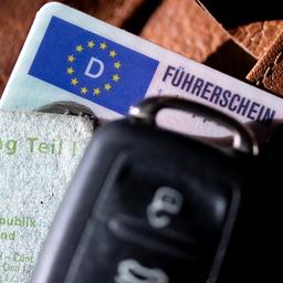 Ein Führerschein, ein Autoschlüssel und eine Zulassungsbescheinigung liegen auf einem Portemonnaie.