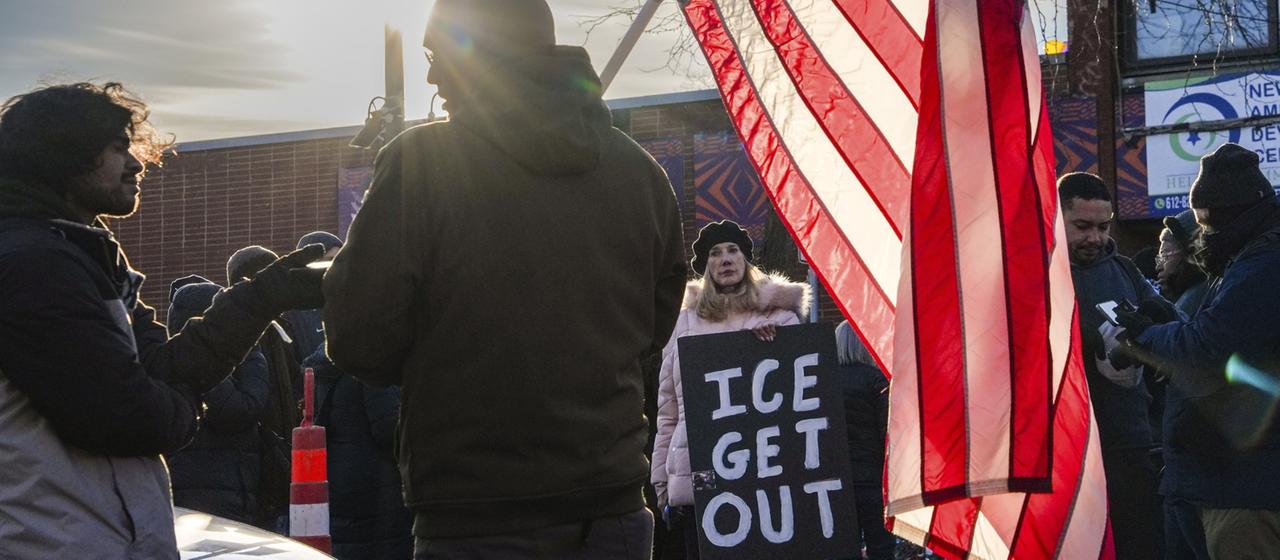 Menschen mit einer US-Flagge und einem Schild mit der Aufschrift "ICE get out"
