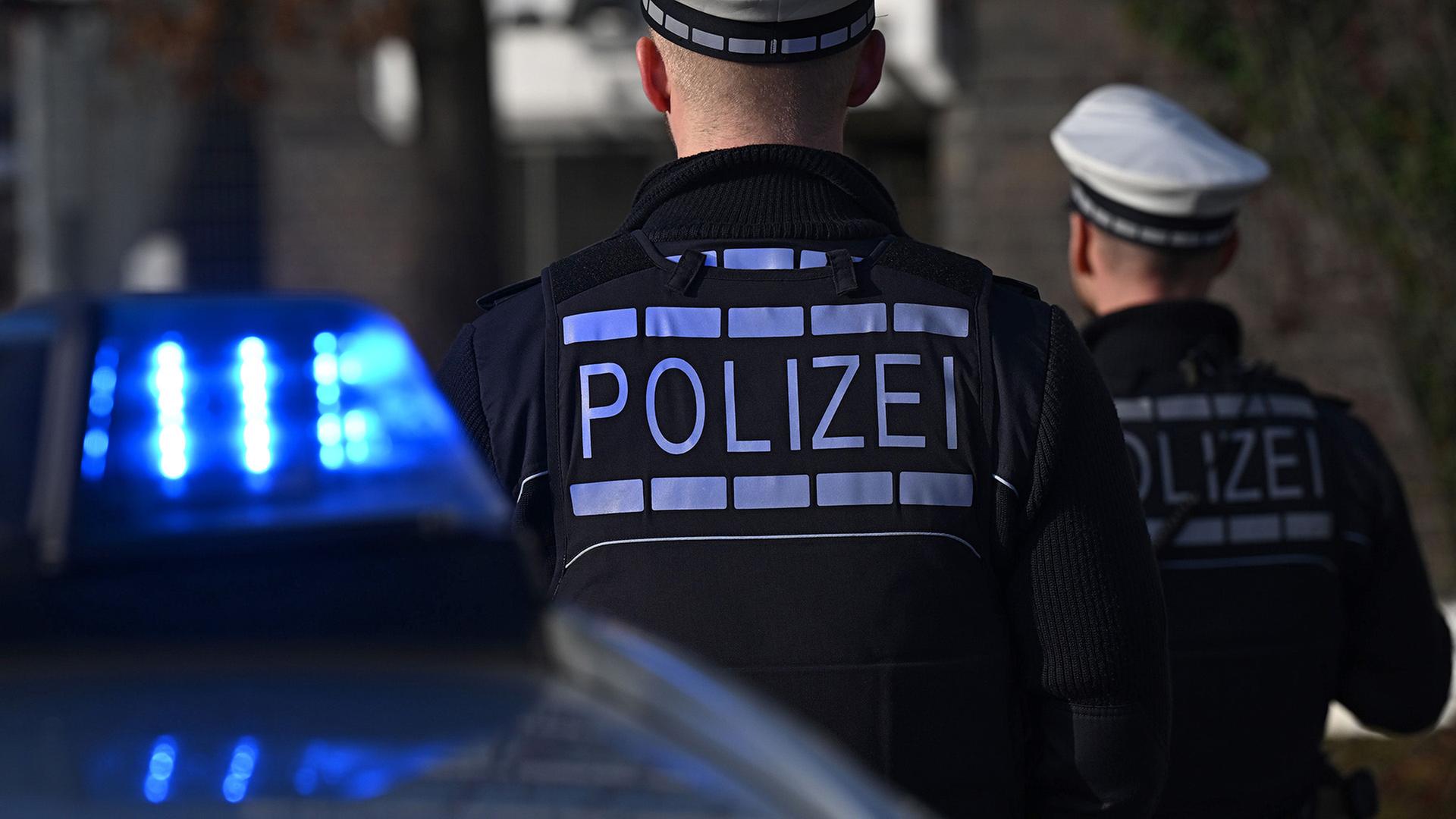 Polizisten die vor einem Blaulicht stehen. | Bernd Weißbrod/dpa