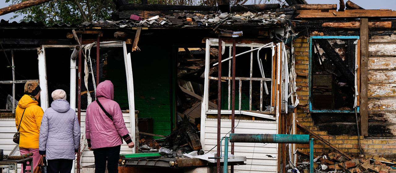 Menschen betrachten in Kiew ein Haus, das bei einem russischen Angriff beschädigt wurde.