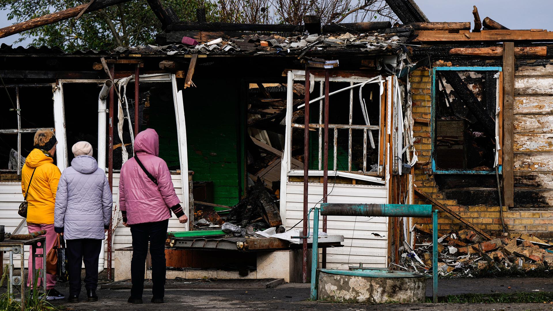 Menschen betrachten in Kiew ein Haus, das bei einem russischen Angriff beschädigt wurde. | AP