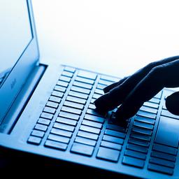 Eine Hand bedient die Tastatur von einem Laptop.