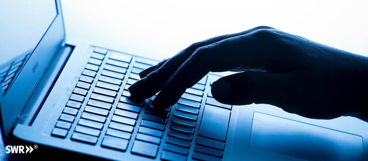 Eine Hand bedient die Tastatur von einem Laptop.