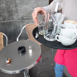 Ein Kellner räumt einen Tisch in einem Restaurant ab. 