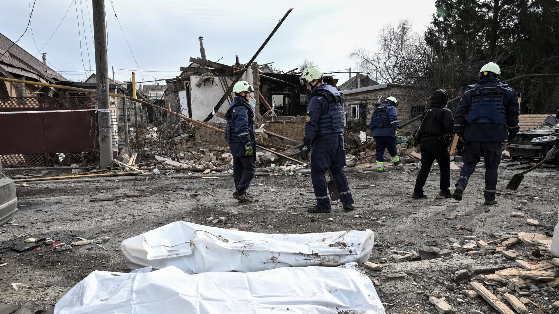 Leichensäcke liegen vor einem zerstörten Gebäude. | REUTERS