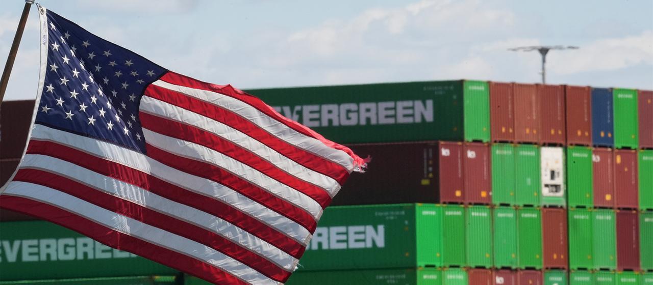 Gestapelte Container im Hafen von Los Angeles, im Vordergrund eine wehende US-Flagge | dpa Gestapelte Container im Hafen von Los Angeles, im Vordergrund eine wehende US-Flagge
