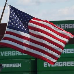 Gestapelte Container im Hafen von Los Angeles, im Vordergrund eine wehende US-Flagge