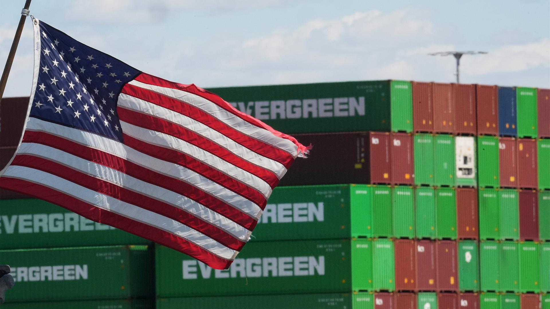 Gestapelte Container im Hafen von Los Angeles, im Vordergrund eine wehende US-Flagge | dpa
