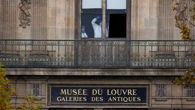 Mitarbeiter der Spurensicherung sind hinter einem Fenster des Louvre zu sehen.