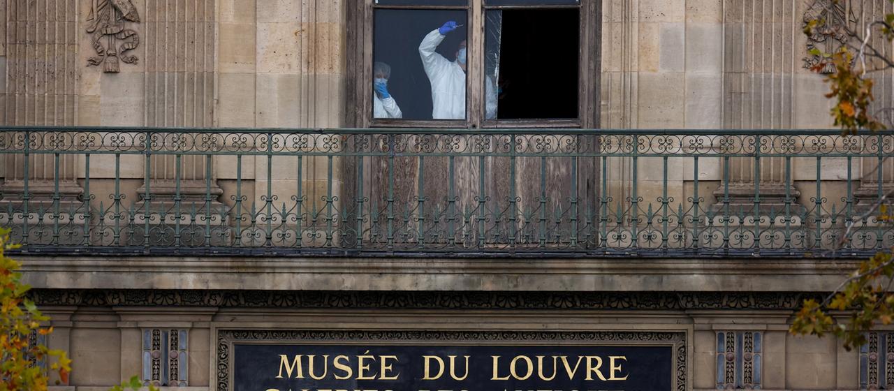 Mitarbeiter der Spurensicherung sind hinter einem Fenster des Louvre zu sehen.