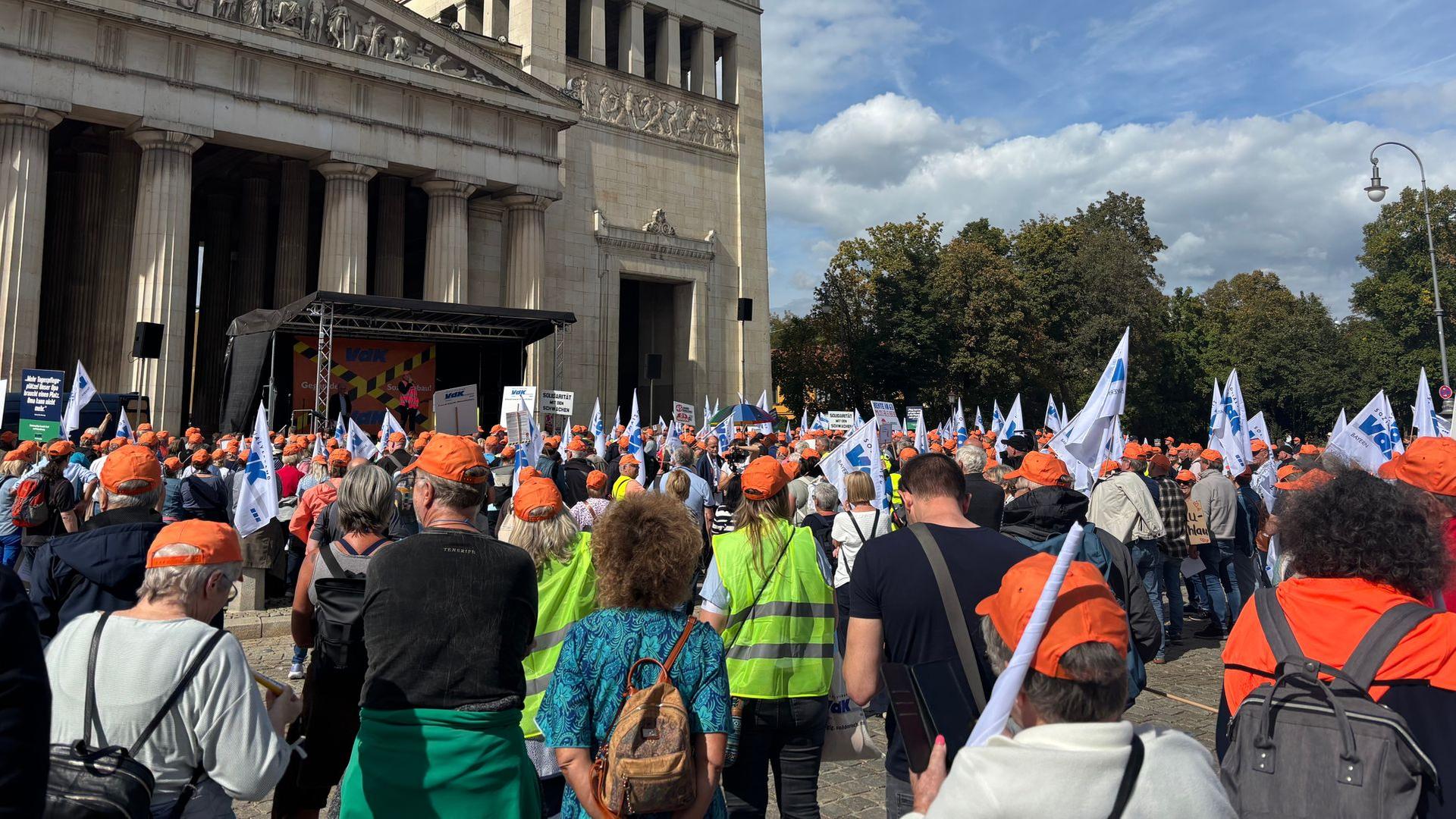Zahlreiche Menschen, teils mit Warnwesten und Fahnen, bei der VdK-Demo auf dem Königsplatz. | Bayerischer Rundfunk 2026