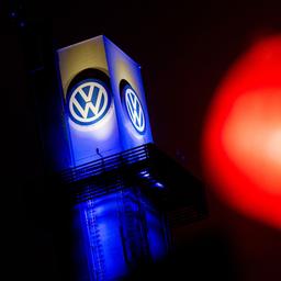 Eine rote Ampel leuchtet vor einem Logo von Volkswagen am Werk Osnabrück. 