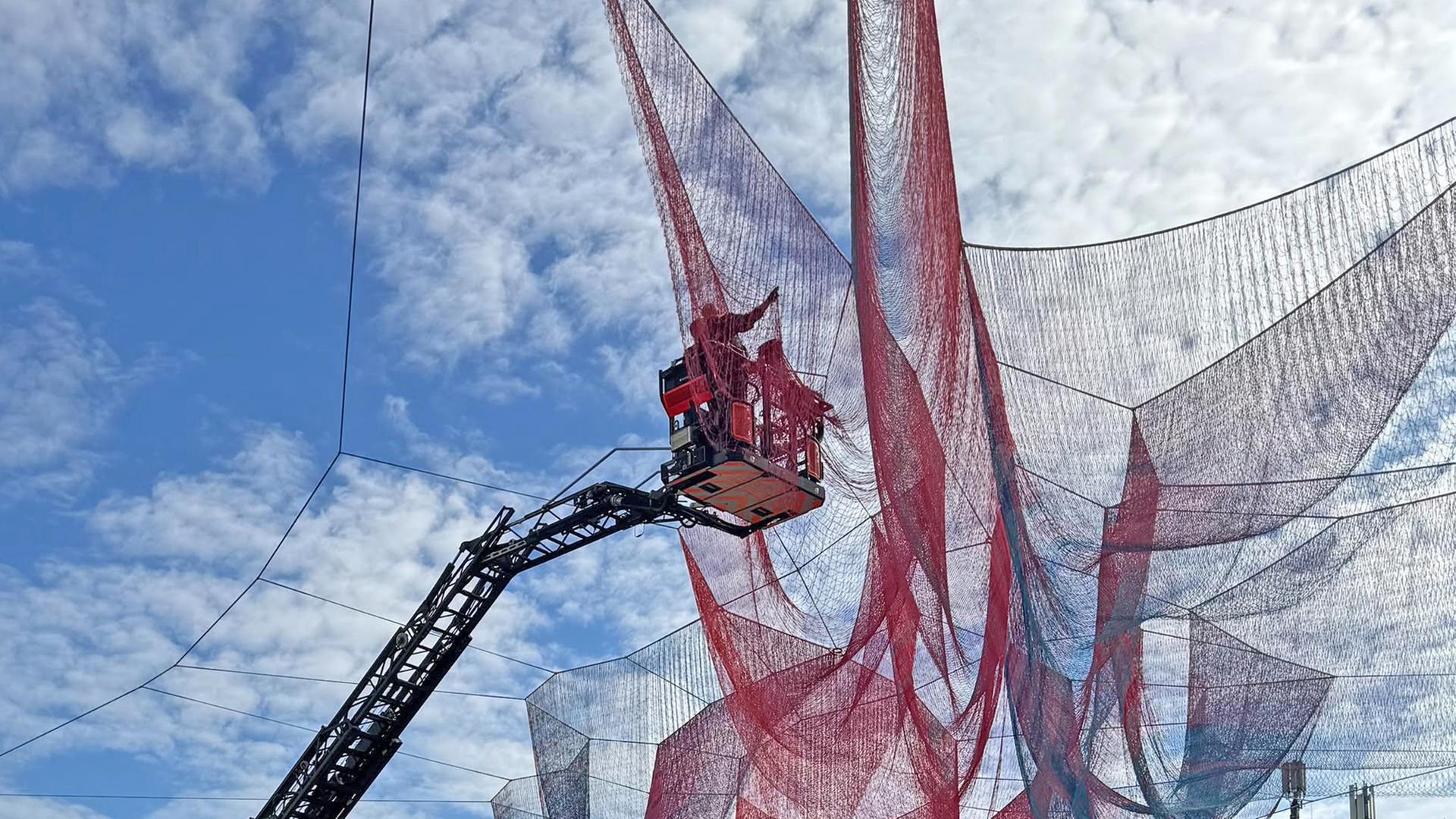 Menschen in einem Steiger arbeiten am Kunstwerk an der Konstablerwache. Der Himmel ist strahlend blau. | ffm.aktuell