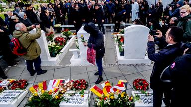 Personen trauern an Gräbern und Gedenksteinen.