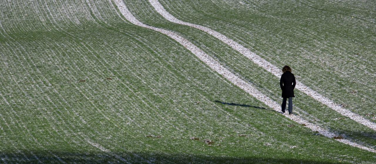 Eine Frau läuft über ein mit einer dünnen Schneeschicht bedecktes Feld bei Mühlen-Eichsen (Nordwestmecklenburg).