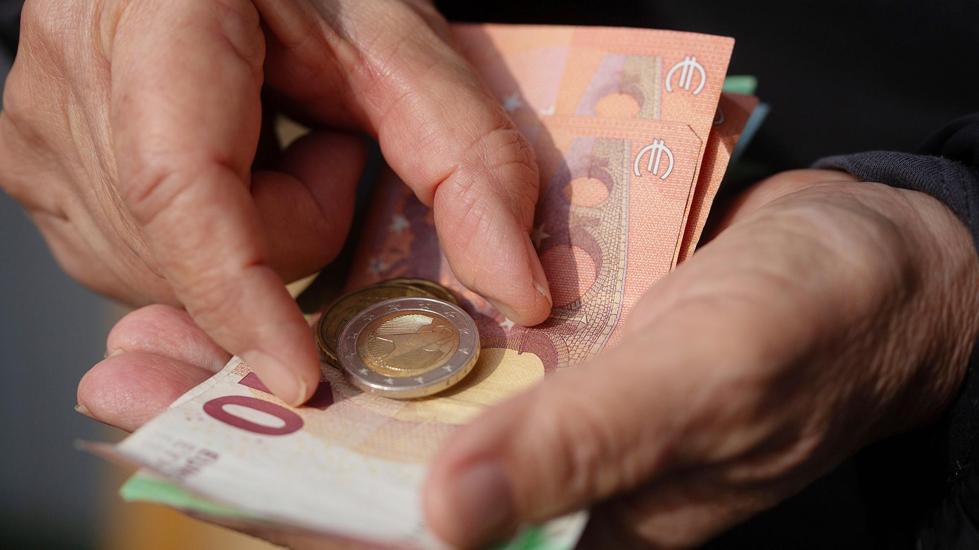 Eine Seniorin hält Euro-Banknoten und Münzen in der Hand. | Fernando Gutierrez-Juarez/dpa