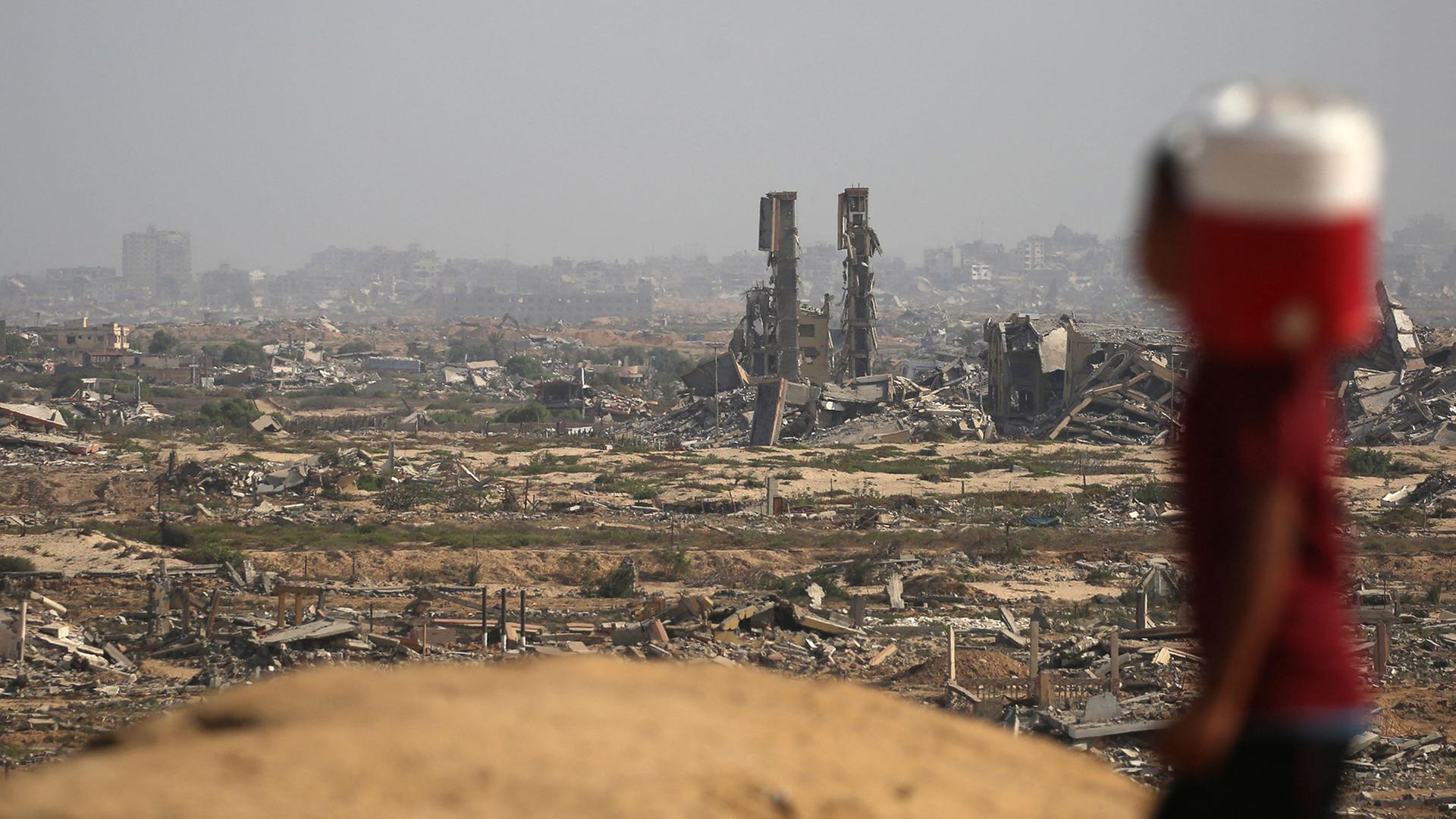 Ein Junge mit einem Wasserkanister vor zerstörten Häusern im Gazastreifen | AFP