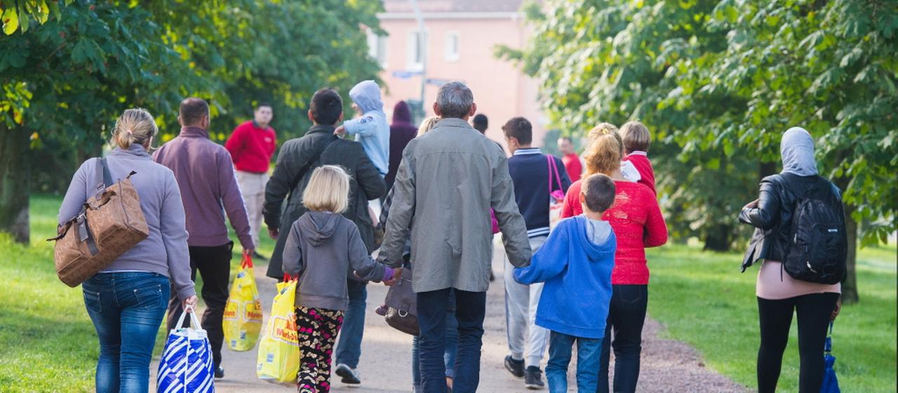 Eine Gruppe von Flüchtlingen geht in Hamburg einen Weg in einer Parkanlage entlang.