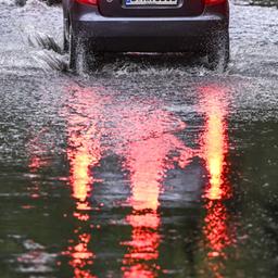 Nach starken Regenfällen fährt ein Auto in Berlin durch eine überspülte Straße