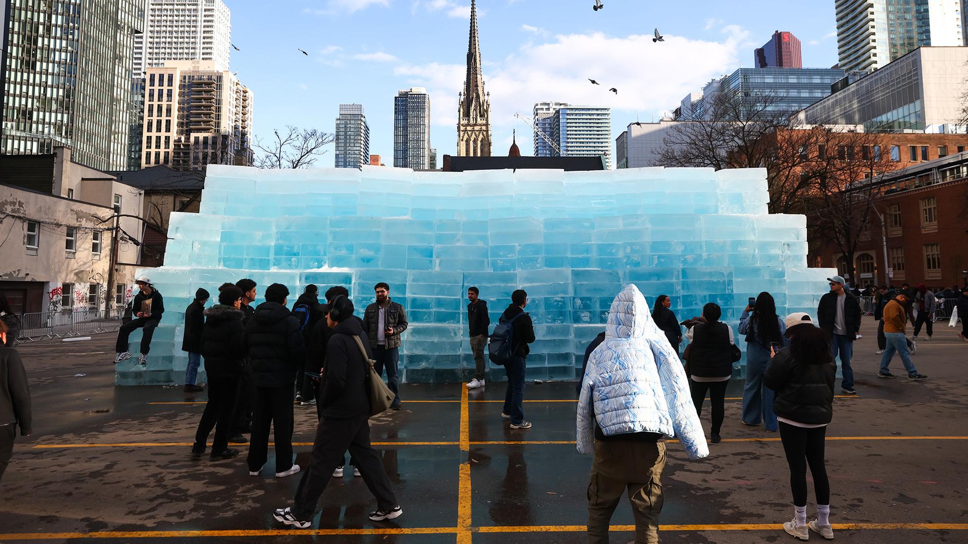 Menschen versammeln sich um EisblÃ¶cke, die auf einem Parkplatz in Toronto aufgestellt wurden. | Cole Burston/The Canadian Press/AP/dpa