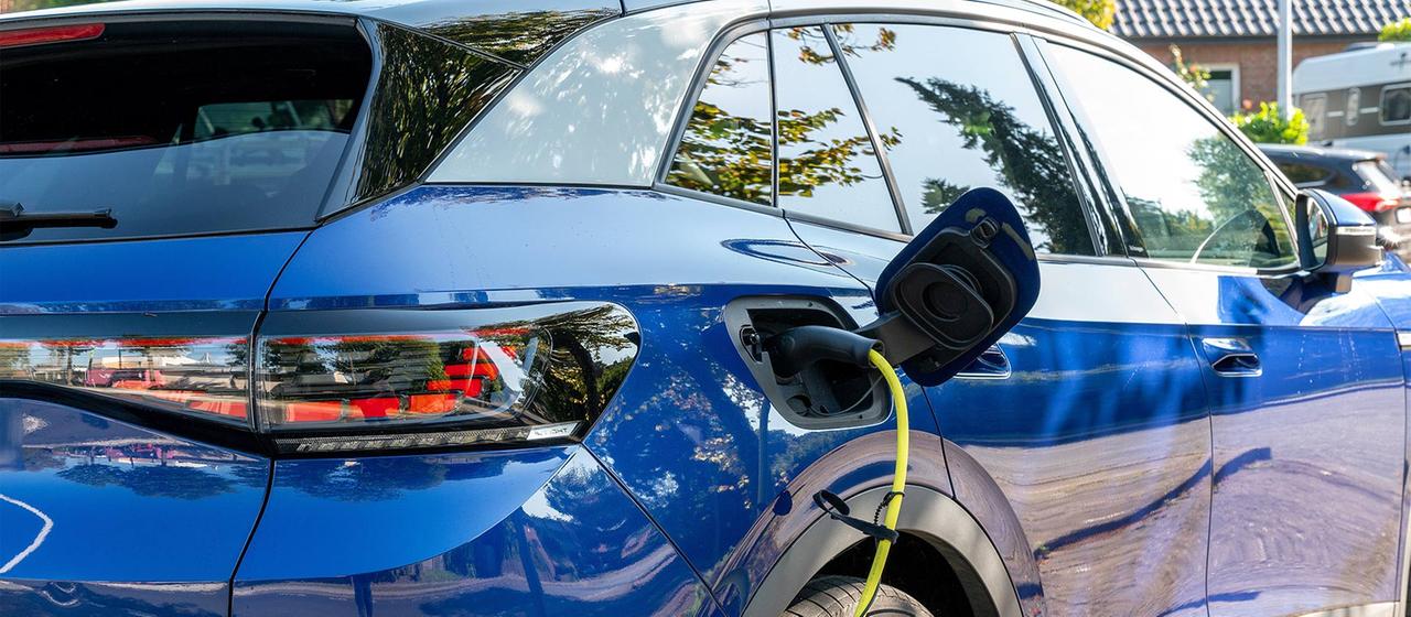 Ein Ladestecker mit gelbem Ladekabel in einem blauen, elektrischen Volkswagen ID.4. 