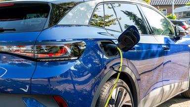 Ein Ladestecker mit gelbem Ladekabel in einem blauen, elektrischen Volkswagen ID.4. 