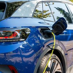 Ein Ladestecker mit gelbem Ladekabel in einem blauen, elektrischen Volkswagen ID.4. 