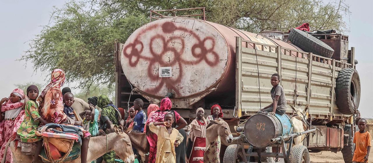 Sudanesische Geflüchtete, die in den Tschad gekommen sind, bekommen Wasser aus einem Wassertank.
