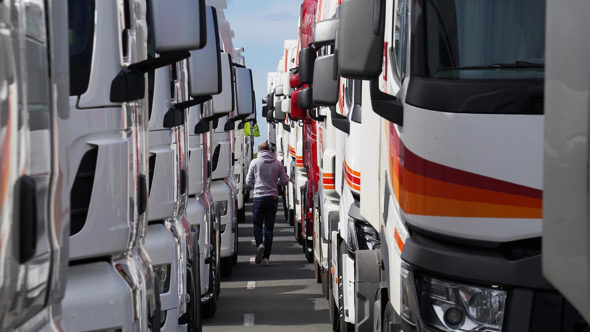 Ein Mann geht zwischen aufgereihten Lastwagen.  | picture alliance/dpa/EUROPA PRES