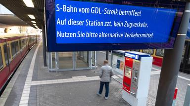 Ein Fahrgast steht auf einem leeren Bahnsteig, während ein Display über den laufenden Streik informiert. 